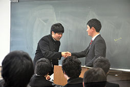 担任との熱い握手で卒業証書を受け取る